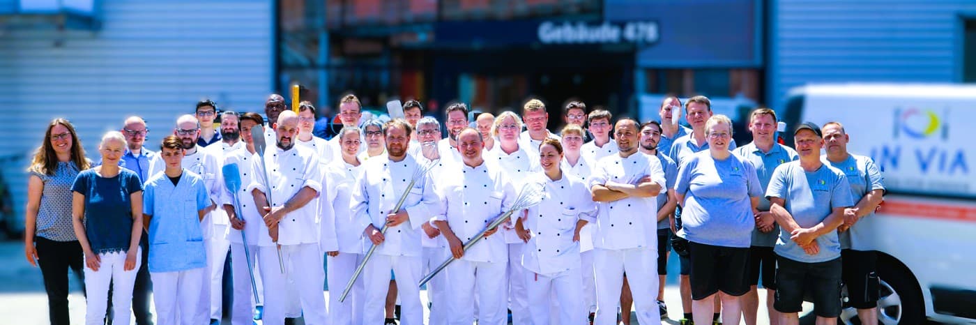 IN VIA Köln Teamfoto mit Küchenpersonal und Mitarbeitern vor Gebäude