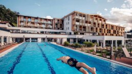 Pletzer Resorts Hotel mit Außenpool und Schwimmer, Bergpanorama im Hintergrund