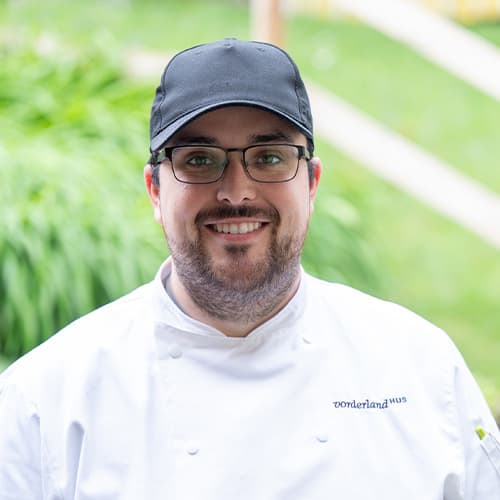 Raphael Huber, K&uuml;chenleiter Vorderlandhus, Portraitfoto in wei&szlig;er Kochuniform